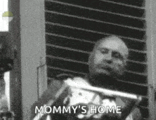 a black and white photo of a man sitting in a chair with the words `` mommy 's home '' written on it .