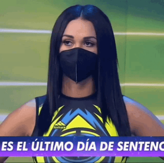 a woman wearing a face mask is standing in front of a sign that says es el ultimo dia de sentenc
