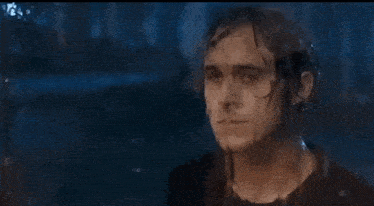 a man is standing in the rain with his head in the water .