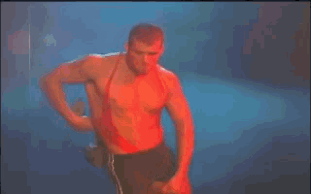 a man without a shirt is dancing on a stage in a dark room .