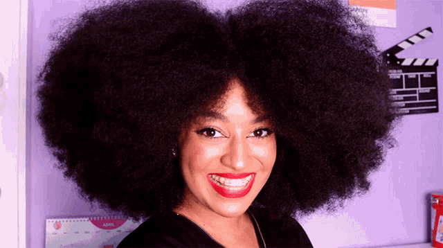 a woman with a large afro is smiling in front of a calendar that says april on it