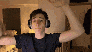 a young man wearing headphones holds his arms up