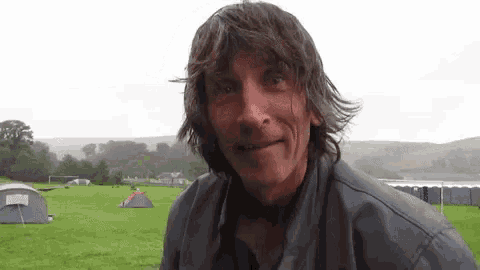 a man is standing in a field with tents in the background
