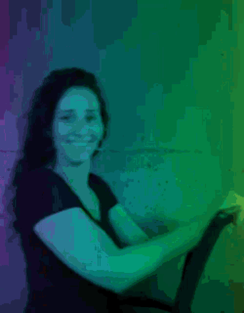 a woman in a black shirt is smiling in front of a green and red wall