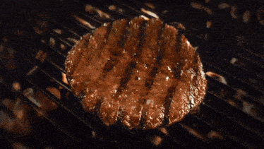 a close up of a hamburger being cooked on a fire