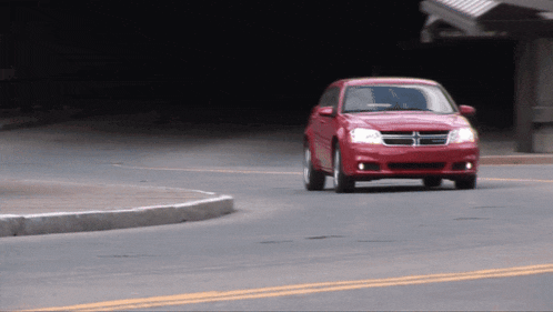 a red dodge minivan is driving down a street