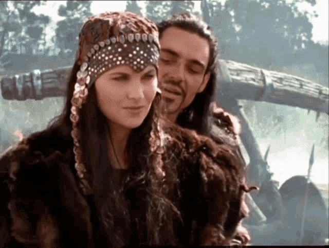 a man and a woman standing next to each other in a forest
