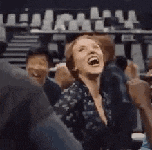 a woman is laughing while sitting in a crowd of people at a concert .