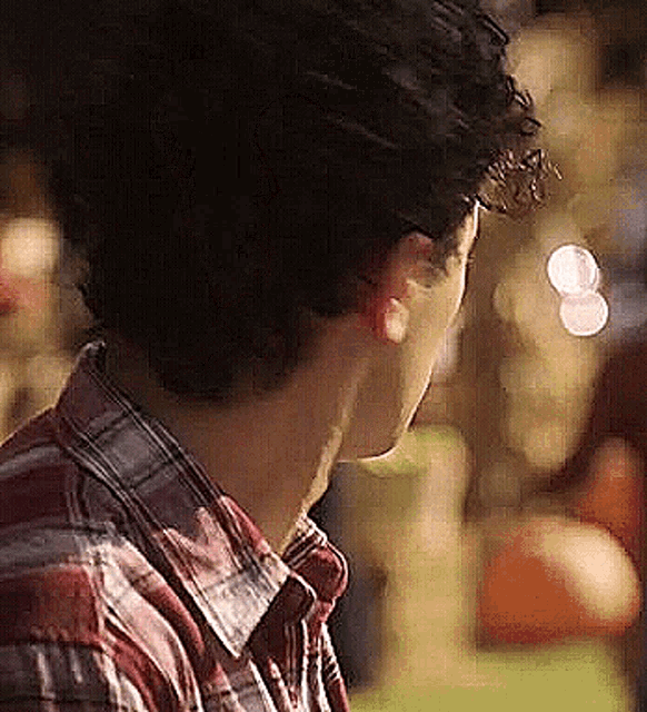a man wearing a plaid shirt is looking down at something