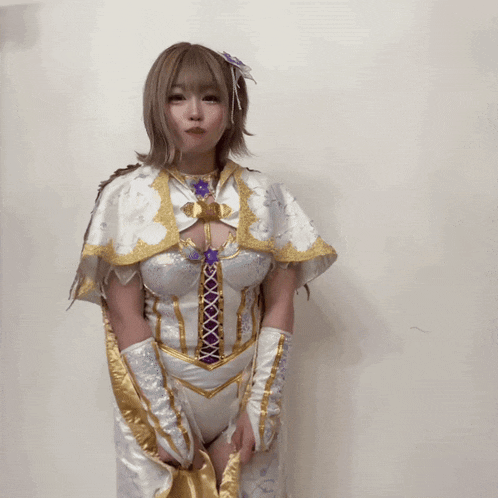 a woman in a white and gold costume is standing in front of a wall
