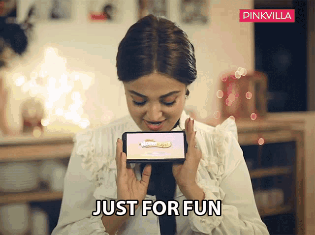 a woman is holding a cell phone with the words just for fun written below her