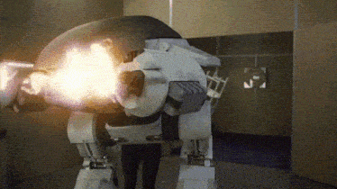 a person standing next to a robot that is shooting bullets