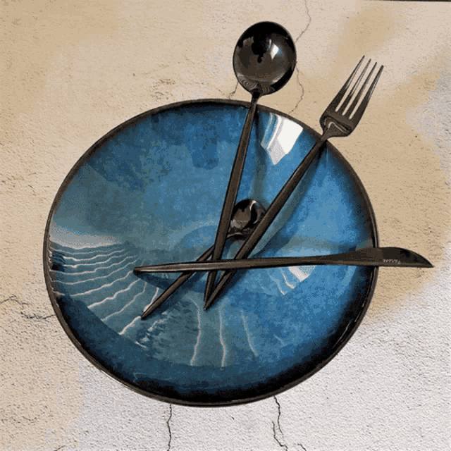 a blue plate with black utensils on it
