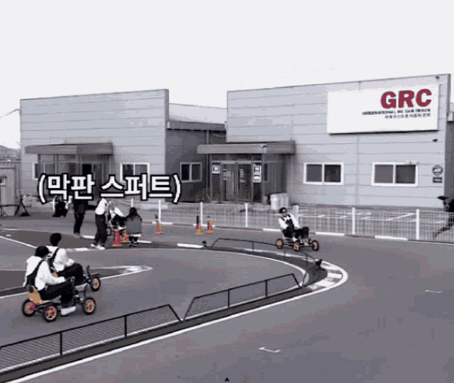 a group of people are riding pedal bikes on a race track in front of a building that says grc