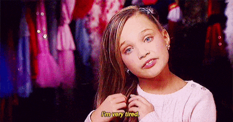 a young girl is holding her hair and saying `` i 'm very tired '' in front of a closet .