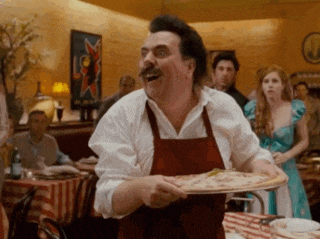 a man in an apron is holding a pizza in his hands