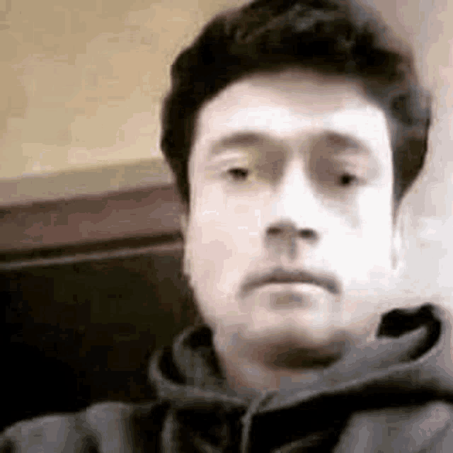 a man in a hoodie is taking a selfie with his phone .