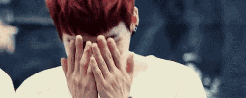 the man is covering his face with his hands .