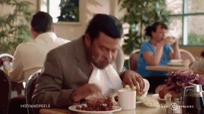 a man in a suit and tie is sitting at a table eating a plate of food .