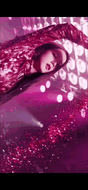 a woman in a red dress is dancing on a stage in front of a bunch of lights .