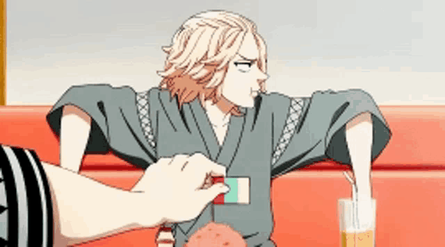a man in a kimono is sitting at a table with a glass of beer and a straw in his hand .