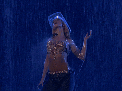 a woman wearing a cowboy hat and jeans is dancing in the rain