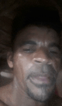 a man with a beard is looking at the camera with his eyes closed and his mouth open .
