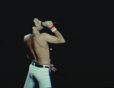 a shirtless man singing into a microphone on stage