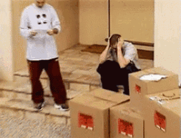 a man standing next to a stack of cardboard boxes with a red label that says ' fragile ' on it