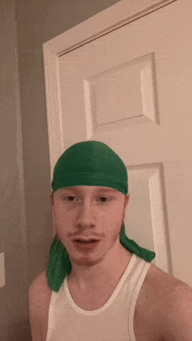 a man wearing a green headband is standing in front of a white door