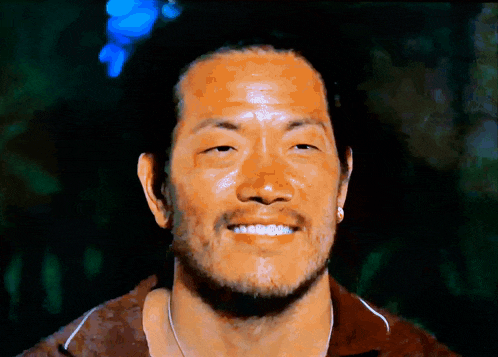 a close up of a man 's face with a beard smiling