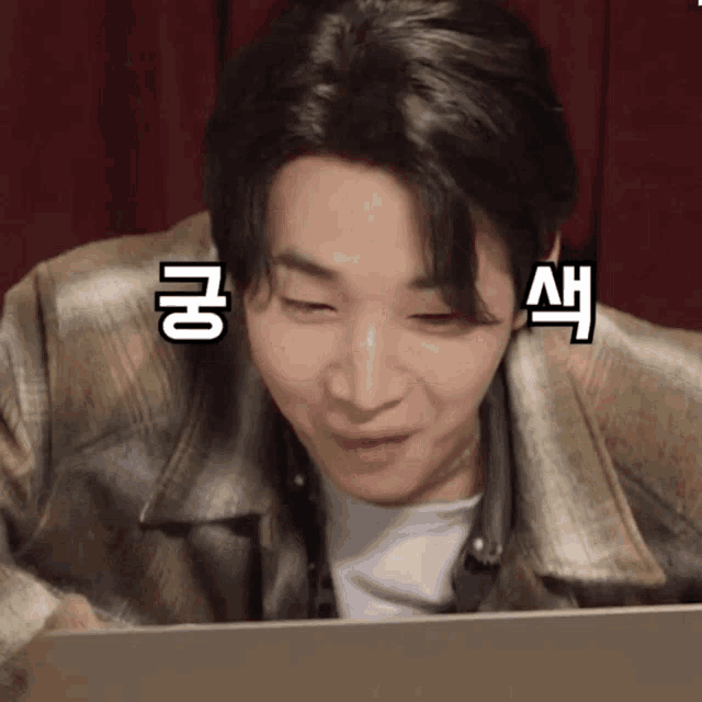 a man in a plaid jacket is looking at a laptop with chinese writing on his face