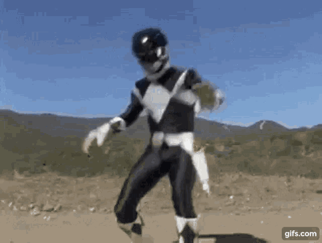 a black and white power ranger is dancing in the dirt .