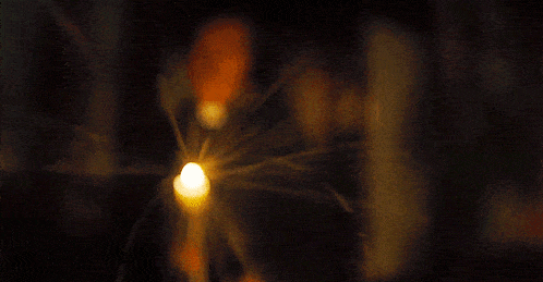 a close up of a lit candle in the dark with smoke coming out of it