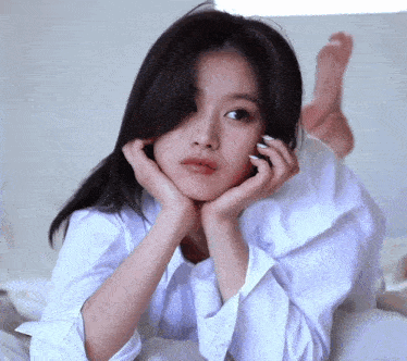 a woman in a white shirt is laying on her stomach on a bed