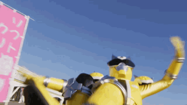 a yellow superhero is waving his hand in front of a pink banner with chinese writing on it