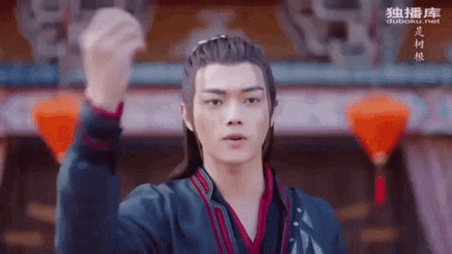 a man in a traditional costume is holding his fist up in the air .