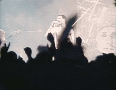 a man singing into a microphone with a crowd behind him