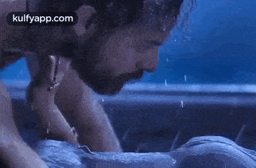 a man is kissing a woman in the rain .