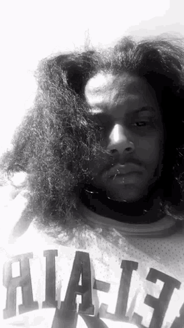 a black and white photo of a man with long hair wearing a jersey that says atlanta