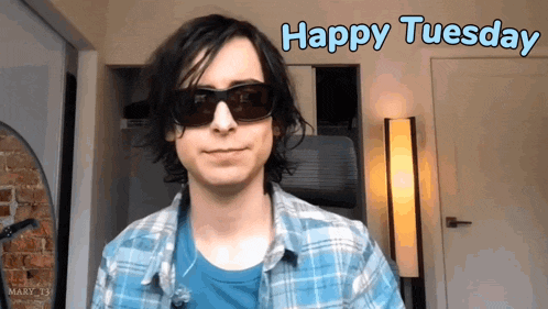 a young man wearing sunglasses and a plaid shirt says " happy tuesday "