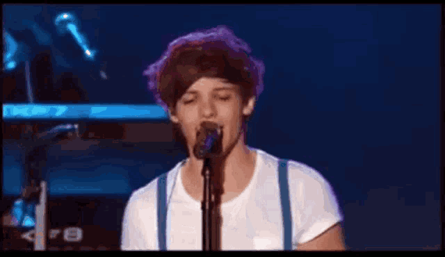 a young man is singing into a microphone on a stage
