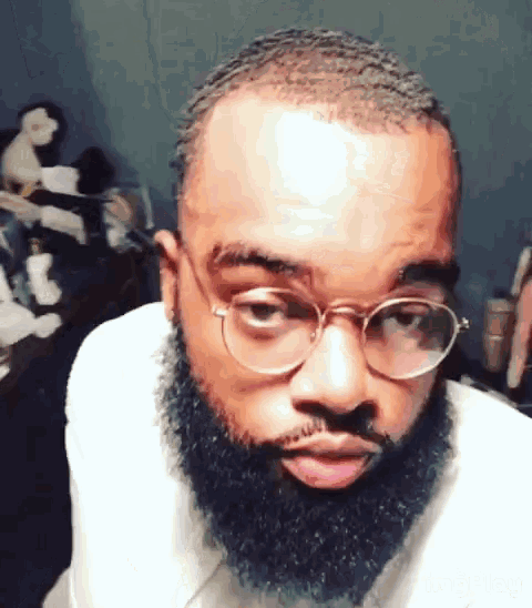 a man with glasses and a beard is making a funny face .