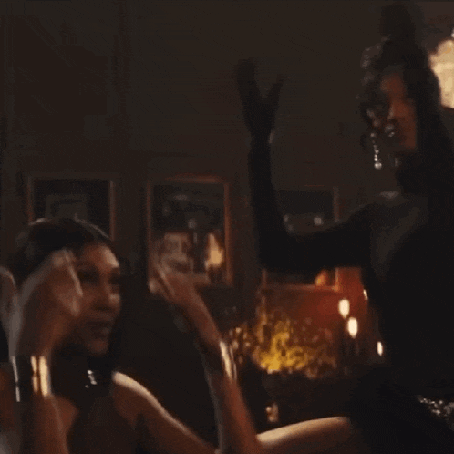 a woman in a black dress is giving a high five to a crowd of people