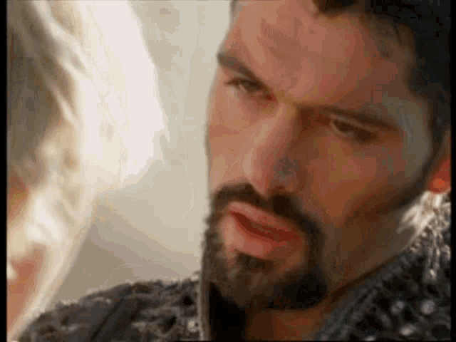 a man with a beard and a black jacket is looking at a woman .
