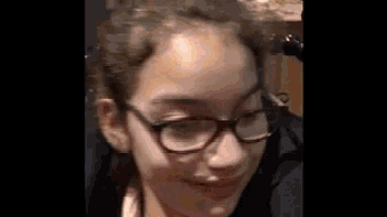 a close up of a young girl wearing glasses and smiling .