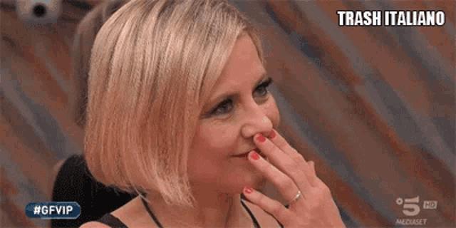 a woman with short blonde hair is smiling and waving her hands .