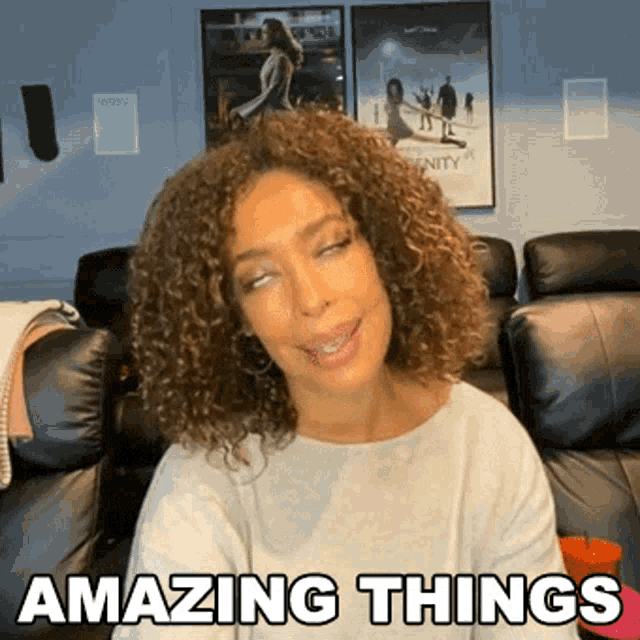 a woman with curly hair is sitting in a living room with the words amazing things above her