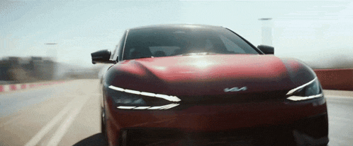a red car with the letters ks on the front is driving down a road