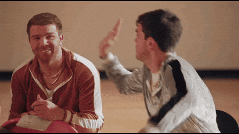 two men are sitting at a table and one of them is pointing